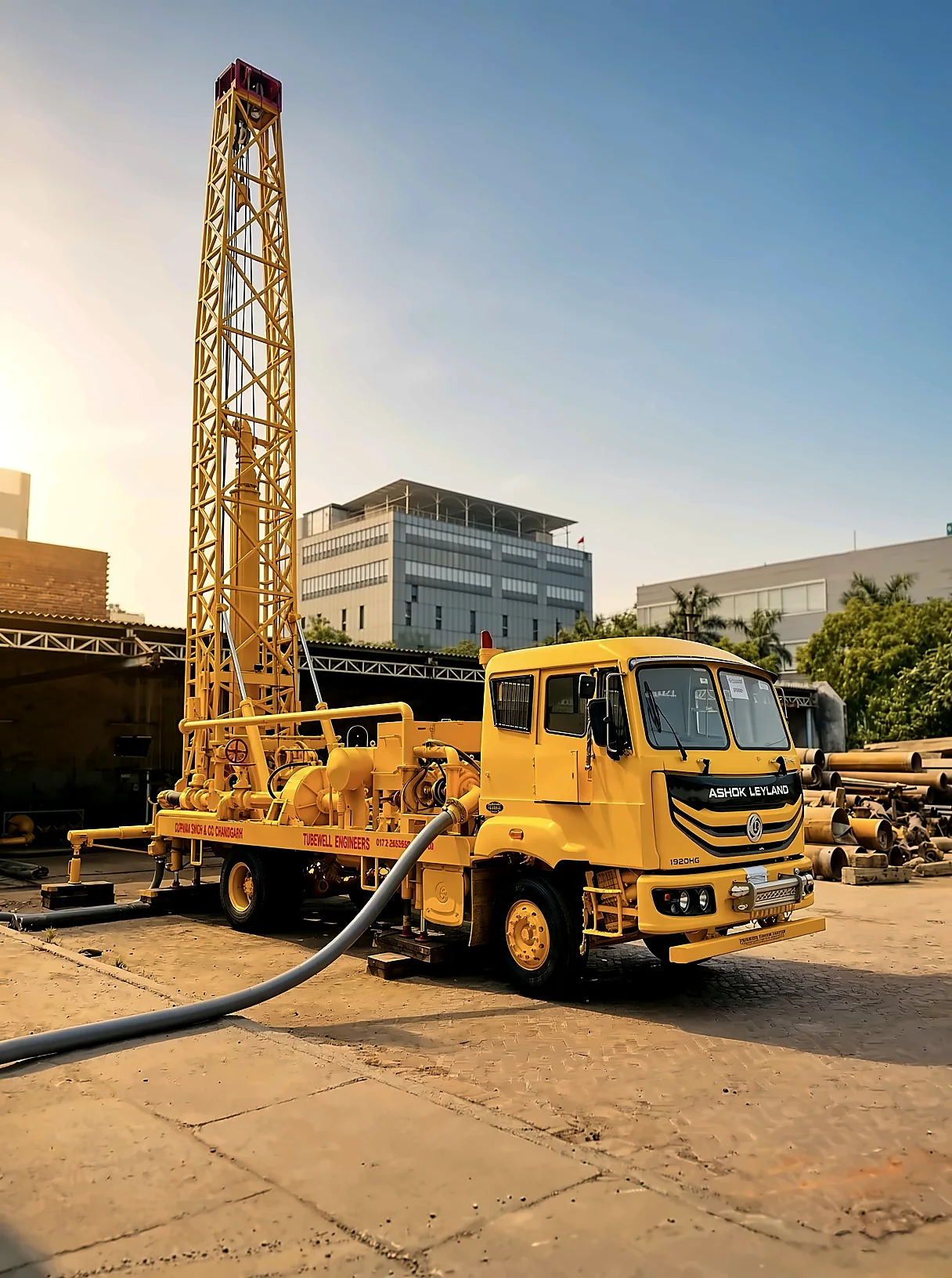 Ashok Leyland 1920HG drilling rig with its mast raised at golden hour, hoses coupled, at the Chandigarh yard